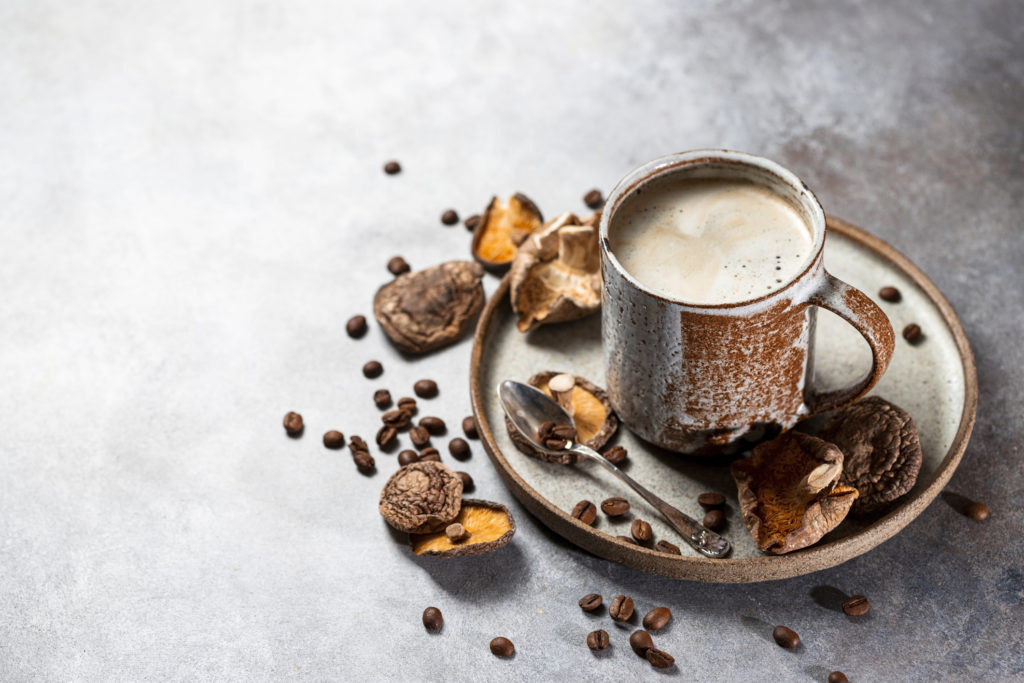 Mushroom coffee, a ceramic cup, mushrooms and coffee beans on stone concrete background. New Superfood Trend.