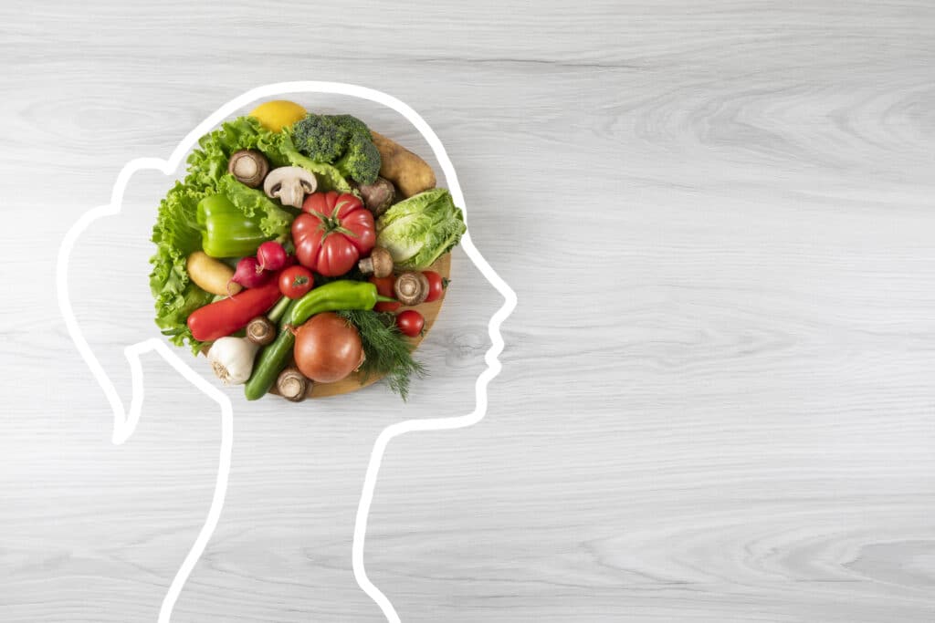 Healthy eating concept with vegetable and human head drawing on gray wooden background with copy space